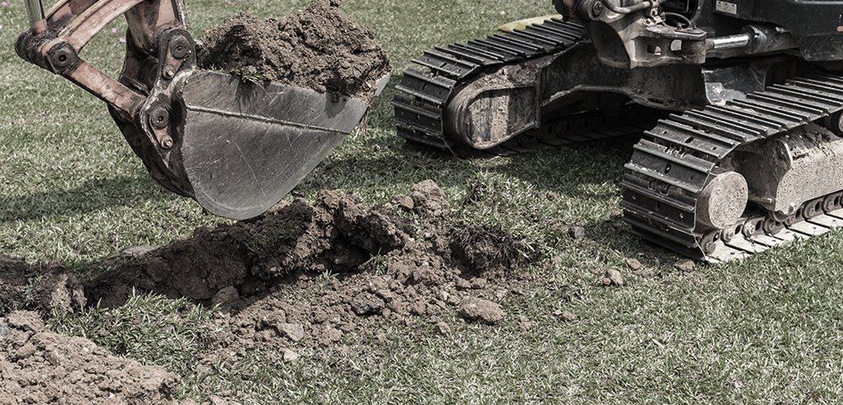 Digging hole in grass with equipment